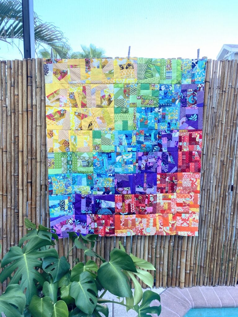 rainbow scrap quilt on a fence